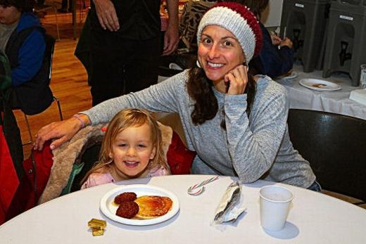 The free hot sausage and pancake breakfast at SMILE Station was a major draw for many, including Arya and her mom Vuri Ford.