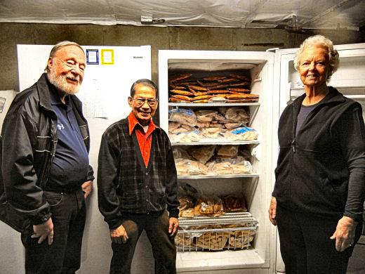 Dominador (Donny) Estrada (at center) received this years Vincentian of the Year award, for being an outstanding volunteer at the OLS food pantry for 40 years. He is shown with a freezer of meat from the Oregon Food Bank, and with Pantry organizers Jim and Karen Meade. 