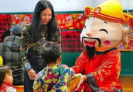 At Sellwood Community Houses Lunar New Year Celebration, Portland Cantonese Play + Learn Founder Theola Wong looked on as Caishen, mythical Chinese God of Wealth, offered his golden coin to be rubbed for luck.