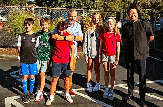 At their Back-to-School Bash, some of the returning students gathered around Holy Family Catholic School Principal Joe Galati, at center, and church pastor Father Rodel de Mesa.