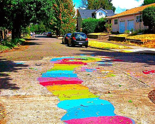 This river of color, painted in the street by kids during a Brooklyn block party, was simply intended to brighten the residential area near the new five-story apartment building thats painted grey  two blocks south of Powell Boulevard, on the east side of Milwaukie Avenue.