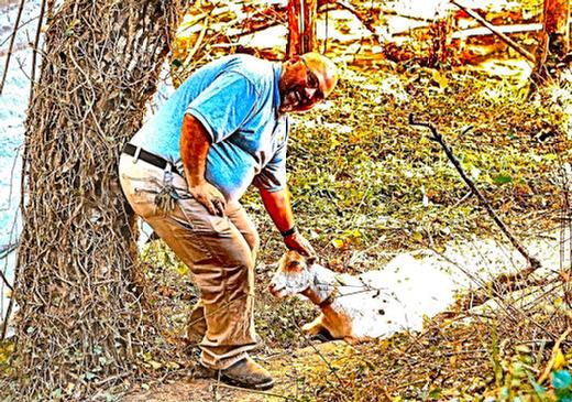 PP&R Golf Course Maintenance Supervisor John Ball says hello to one of the goats  which, at the time, was taking a well-earned break from its brush-clearing duties in a ravine at the Eastmoreland Golf Course.