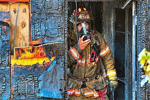 Covered in soot and debris, this Woodstock Fire Station 25 Ladder Truck Company firefighter walks out of the burned house breathing through an oxygen mask.