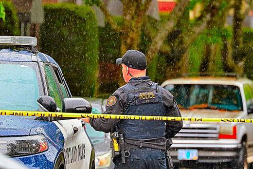 Amidst falling rain, a Central Precinct officer kept watch on an area near OMSI, as a man reported to be menacing with a weapon was hiding in bushes and refusing to surrender to police. He eventually was taken into custody near the science museum.