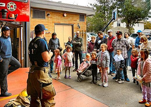 Firemen F.F. Ross [far left] and A.J. shared very important safety advice, and displayed their fire tools, for Woodstock Elementary School parents and children on a mid-October Woodstock Walks visit to Fire Station 25.